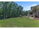 Backyard with expansive lawn, mature trees and patio with lounge furniture and flower garden at 295 Cedar Rock Trl, Fuquay Varina, NC 27526