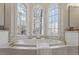 Bright bathroom showcasing a soaking tub beneath three large windows offering serene outdoor views at 302 Edinburgh Dr, Cary, NC 27511
