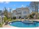 A stunning backyard featuring a pristine blue pool, with a white home and luscious green landscaping at 302 Edinburgh Dr, Cary, NC 27511