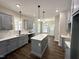 Well-lit kitchen with gray cabinets, a center island, stylish fixtures, and hardwood-style floors at 314 S Darden St, Kenly, NC 27542