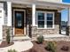 Inviting front entrance with a decorative wood door, stone accents, white columns, and manicured landscaping at 353 Murray Grey Ln, Wake Forest, NC 27587