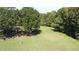 This aerial shot captures the charming home nestled among mature trees, a lush lawn and a tranquil pond at 4322 Russell Rd, Graham, NC 27253