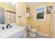 A yellow bathroom with a marble top vanity, toilet, and tiled floors at 4322 Russell Rd, Graham, NC 27253