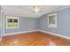 Bright bedroom with hardwood floors, two windows and soft blue walls at 4322 Russell Rd, Graham, NC 27253