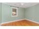A bedroom with hardwood floors, a window, and white trim with light green walls at 4322 Russell Rd, Graham, NC 27253