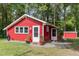 Quaint red outbuilding with white trim and dual entrances, surrounded by lush greenery at 4322 Russell Rd, Graham, NC 27253