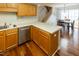 Kitchen area with wood cabinets, leading to a dining area and staircase, featuring hardwood floors at 5420 Golden Moss Trl, Raleigh, NC 27613