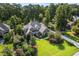Aerial view of a brick home with mature trees, lawn, and lush landscaping at 5708 Creekfall Ln, Fuquay Varina, NC 27526