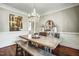 Light-filled dining room with a large wooden table, decorative chandelier, and hardwood floors at 5708 Creekfall Ln, Fuquay Varina, NC 27526