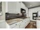 Kitchen boasts granite counters, dark backsplash, white cabinets and stainless appliances at 5708 Creekfall Ln, Fuquay Varina, NC 27526