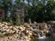 Stone community entrance feature with lush landscaping, decorative boulders and a small waterfall at 59 Riverstone Dr, Pittsboro, NC 27312