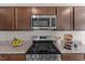 Close-up of the kitchen's stainless steel oven and gas cooktop with granite countertops and wood cabinets at 669 Impala Trce, Wendell, NC 27591