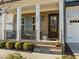 Inviting front porch with brick steps, white columns, and a dark wood door with glass panes at 1027 Laurelwood Dr, Durham, NC 27705