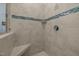 Spacious shower with stone surround, corner seat and horizontal blue accent tiles at 1027 Laurelwood Dr, Durham, NC 27705