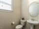 Half bathroom featuring pedestal sink, toilet, and window at 1028 Dotson Way, Apex, NC 27523