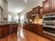 Modern kitchen with hardwood floors, stainless steel double oven, granite countertops, and dark wood cabinetry at 1028 Dotson Way, Apex, NC 27523