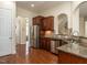 Open kitchen featuring hardwood floors, stainless steel refrigerator, granite countertops, and dark wood cabinets at 1028 Dotson Way, Apex, NC 27523