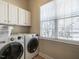 Bright laundry room with white washer, dryer, cabinets, and large window at 1028 Dotson Way, Apex, NC 27523