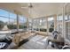 Sunroom with tile floors, ceiling fan, large windows, and comfortable seating with blue and white striped pillows at 109 Skywater Ln, Holly Springs, NC 27540