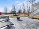 Backyard stone patio with fire pit and lounge chairs; playground in the distance, a perfect spot for entertaining at 115 Lockamy Ln, Youngsville, NC 27596