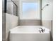Relaxing soaking tub with tile surround and a bright, natural light from the window at 115 Lockamy Ln, Youngsville, NC 27596