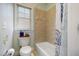 Full bathroom with a shower-tub combination, tiled walls, and a window providing natural light at 12345 Beestone Ln, Raleigh, NC 27614
