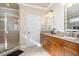 Bathroom featuring double vanity with granite countertop, wood cabinets, and walk-in shower with glass door at 12345 Beestone Ln, Raleigh, NC 27614