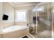 Luxurious bathroom with a soaking tub, separate glass-enclosed shower, and tiled surround at 12345 Beestone Ln, Raleigh, NC 27614