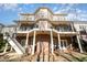 Multi-level rear exterior view of home with balconies, brick pillars, and staircase to the landscaped backyard at 12345 Beestone Ln, Raleigh, NC 27614