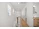 Well-lit hallway with hardwood floors, white walls, and access to a full bathroom at 1410 Joe Louis Ave, Raleigh, NC 27610