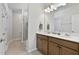 Bathroom featuring double sinks with stone countertop, hardwood cabinets, and frameless glass shower at 1413 Buxus Ct, Fuquay Varina, NC 27526