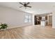 Open-concept living room with hardwood floors, ceiling fan, large windows and view of the kitchen at 1413 Buxus Ct, Fuquay Varina, NC 27526