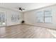 Empty living room with hardwood floors, light-colored walls, ceiling fan, large windows and view of the yard at 1413 Buxus Ct, Fuquay Varina, NC 27526