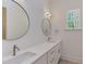 Bright bathroom with dual sinks, white countertops, stylish mirrors and a view of the outdoors through the window at 15 Harvest View Way, Franklinton, NC 27525
