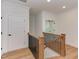 Upstairs hallway with wood floors, doors, and staircase with black railings at 15 Harvest View Way, Franklinton, NC 27525