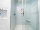 Tiled shower area with a glass enclosure, built-in shelves, and a nearby laundry unit at 1603 Sutton Dr, Raleigh, NC 27605