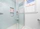 Walk-in shower with light blue tiles, a built-in shelf, and a glass door at 1603 Sutton Dr, Raleigh, NC 27605