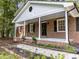 Inviting brick front porch with classic columns and manicured landscaping at 208 Hardwood Ridge Ct, Clayton, NC 27520