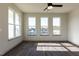 Sunlit living room with three windows offering neighborhood views, enhanced by dark wood floors and a ceiling fan at 2300 Gathering Sq Ct, Fuquay Varina, NC 27526