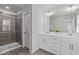 Modern bathroom featuring double sinks, a large mirror, and a tiled shower with glass door at 2440 Tonoloway Dr, Raleigh, NC 27610