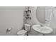 A well-lit half bathroom featuring a pedestal sink, circular mirror, and neutral wall color at 2440 Tonoloway Dr, Raleigh, NC 27610