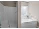 Bright bathroom features a standalone shower and a luxurious soaking tub beneath a window at 40 Paddle Wheel Ct, Franklinton, NC 27525