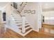 Entryway staircase boasts hardwood steps, white risers, and flows to the kitchen with white cabinetry at 44 Ashwood Dr, Chapel Hill, NC 27516