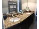 Bathroom with a dual sink vanity featuring granite counters, decorative shelves, and a large mirror at 4401 Sprague Rd, Raleigh, NC 27613