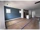 Unfurnished living space with blue accent wall, large windows, and kitchen with island in the background at 504 Yeowell Dr, Chapel Hill, NC 27514