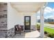 Inviting covered front porch with stone accents, seating, and view of neighborhood street at 52 Commons Cir, Clayton, NC 27520