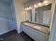 Bathroom featuring a granite vanity with dual sinks, mirrors, and wood-look flooring at 52 Commons Cir, Clayton, NC 27520