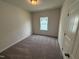 Bright bedroom features neutral walls, cozy carpet, and a window allowing natural light at 52 Commons Cir, Clayton, NC 27520