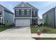 Two-story home featuring a gray exterior, white garage door, and manicured front yard with 'Must See Upgrades' sign at 52 Commons Cir, Clayton, NC 27520