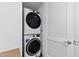Modern, stacked, front-load washer and dryer in a laundry closet with louvered door at 523 S West St # 409, Raleigh, NC 27601